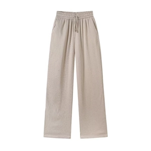 Detail of light beige wide-leg pants featuring vertical ribbed texture and drawstring waist