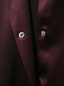 Detail of silver metal snap button on smooth deep purple satin shirt jacket fabric