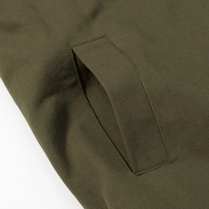 Detailed macro view of military green twill fabric and reinforced pocket stitching on jacket