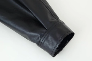 Vue détaillée du poignet à double couture sur une veste en cuir PU noir à grain litchi