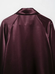 Close-up detail of smooth satin fabric texture on a burgundy silk-like shirt jacket