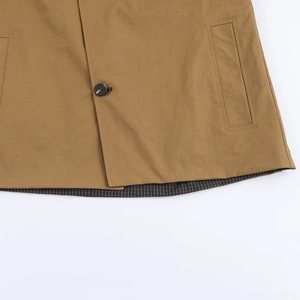 Close-up of khaki reversible windbreaker featuring black button and striped lining details