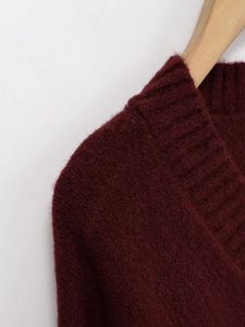 Détail de la maille côtelée rouge vin et de la couture d'épaule d'un pull à col en V