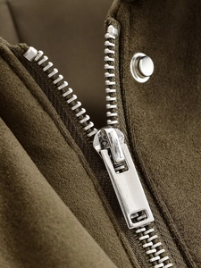 Macro detail of silver metal zipper and snap button on faux suede jacket fabric