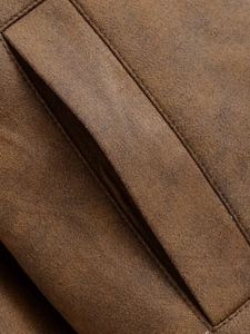 Vue détaillée des coutures et de la texture douce d'une veste en daim marron de qualité