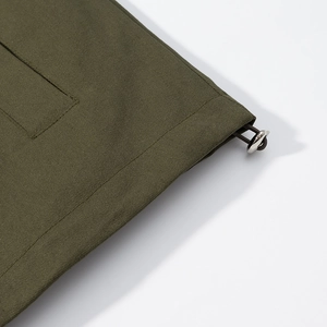 Detail of olive green twill jacket hem featuring a silver metal toggle and elastic drawstring