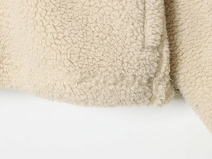 Gros plan sur la texture du tissu polaire sherpa crème avec détails de couture précis