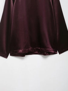 Detail of burgundy satin jacket hem showing smooth silk-like texture and neat stitching
