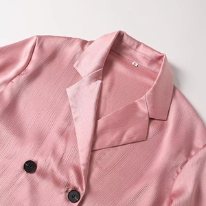 Detail view of pink pleated satin blazer featuring black buttons and S size label