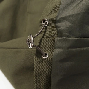 Detail of army green jacket showing metal cord lock, elastic drawstring and twill fabric