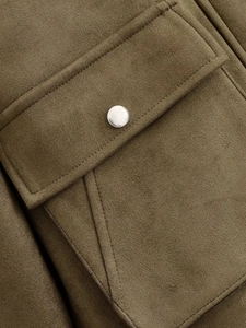 Detail of army green faux suede jacket featuring a flap pocket with a silver metal button