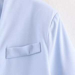 Dettaglio ravvicinato di un blazer slim azzurro da donna con taschino e trama del tessuto