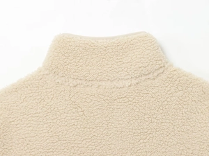 Détail de la texture polaire crème haute densité sur une veste à col montant