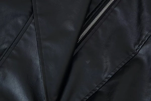 Détail macro de la veste en cuir PU noir montrant la fermeture éclair en métal argenté