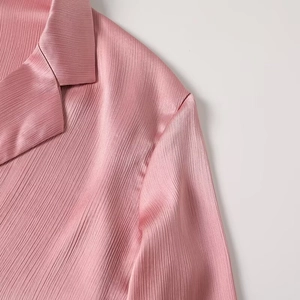 Detail of pink satin blazer showing fine vertical pleats and tailored collar design