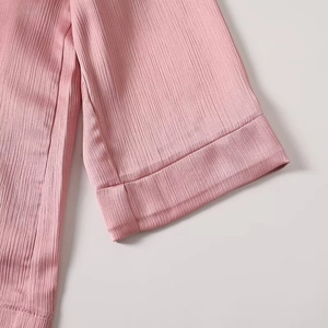 Close-up of pink blazer sleeve featuring vertical textured fabric and folded cuffs