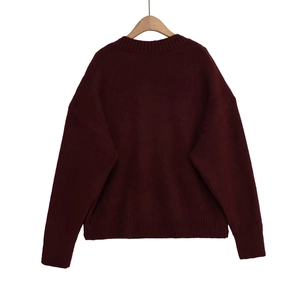 Détail d'un pull en maille rouge foncé avec poignets côtelés et coupe décontractée