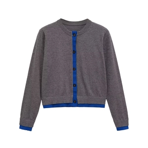 Detail view of round neck knit cardigan with contrasting royal blue trim and buttons