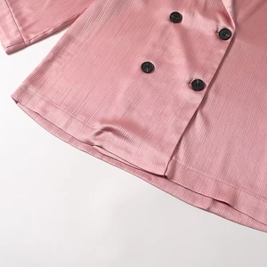 Detailed close-up of pink ribbed fabric texture and black buttons on a blazer suit