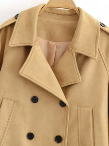 Detail of camel double-breasted coat featuring peak lapels and contrasting black buttons