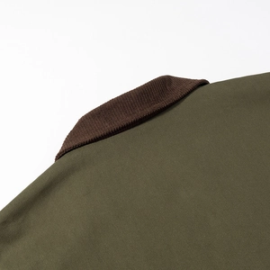Close-up of contrast brown corduroy collar on a dark green zip-up jacket with precise stitching