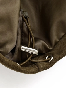 Macro detail of olive green bomber jacket with silver metal toggle and drawstring