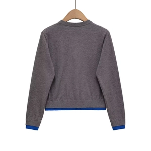 Detail of grey knit cardigan featuring blue ribbed cuffs and layered hem design