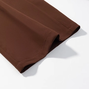 Detailed close-up of dark brown suit fabric with clean flat-stitched hem and smooth texture