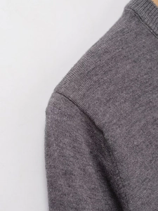 Detail view of the fine knit gray sweater showing the shoulder seam and ribbed collar texture