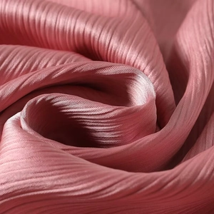 Close-up of pink pleated fabric texture with elegant silky luster and fine vertical folds