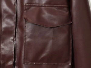 Gros plan d'une veste en similicuir bordeaux avec une grande poche à rabat et coutures soignées