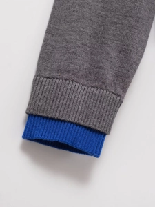 Close-up of grey knit cardigan sleeves with layered blue ribbed cuffs detail