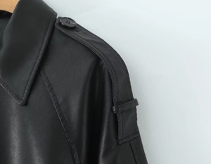 Close-up of black PU leather jacket shoulder featuring strap detail and neat stitching