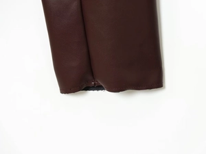 Détail de la veste en cuir PU bordeaux montrant les coutures du poignet et la doublure