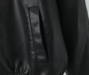 Detailed macro view of black PU leather jacket pocket with vertical piping and hem pleats