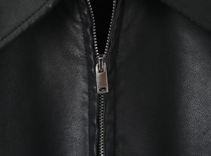 Close-up of a silver metal zipper on a black faux leather jacket with pebble texture