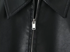Detailed close-up of the lapel structure and silver metal zipper on the black PU jacket
