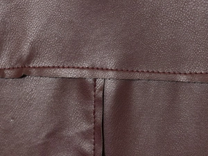 Gros plan sur le cuir PU bordeaux montrant le grain détaillé et les coutures renforcées
