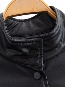Close-up of the stand collar and snap buttons on a black faux leather jacket detail
