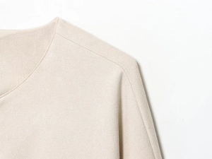 Détail de l'encolure de la veste de baseball crème avec texture fine et couture
