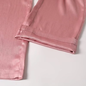 Detailed close-up of pink trousers hem showing vertical texture and silk-like glossy fabric