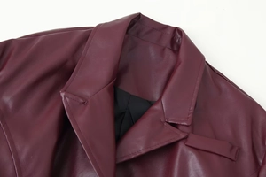 Détail du col à revers et des coutures sur une veste cintrée en similicuir bordeaux