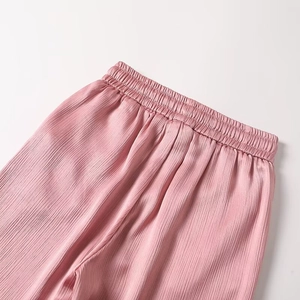 Close-up of pink pleated pants showing elastic waistband and vertical wrinkled fabric texture