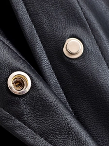 Close-up of litchi texture faux leather fabric and silver metal snap buttons on jacket