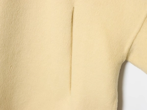 Detail of invisible pocket seams on beige wool-like jacket fabric with soft brushed texture