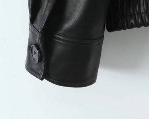 Detailed macro view of black PU leather jacket cuff with button and elastic hem finish