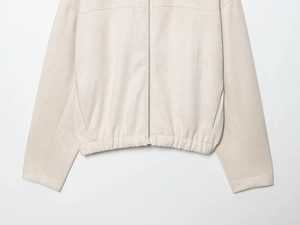 Gros plan d'une veste en daim beige avec fermeture éclair argentée et détails à l'ourlet