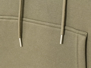 Détail d'un sweat à capuche vert olive avec cordons, embouts métalliques et coutures