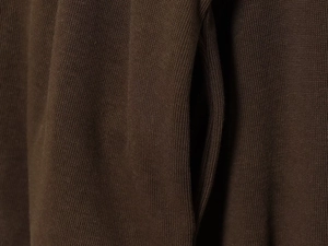 Detailed macro view of soft brown knitted fabric texture and premium stitching on a zipper jacket