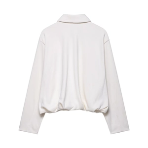 Detail of white pleated velvet bomber jacket showing the polo collar and smooth texture